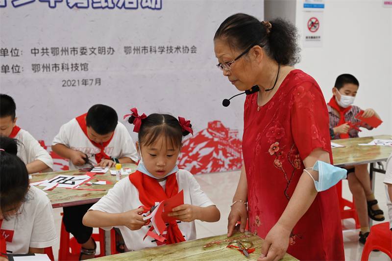 2021年7月10日，鄂州市科協(xié)組織落駕坪小學(xué)學(xué)生在鄂州市科技館開(kāi)展社會(huì)主義核心價(jià)值觀系列活動(dòng)，圖為開(kāi)展的紅色剪影圓夢(mèng)中華剪紙活動(dòng)，老師指導(dǎo)同學(xué)剪紙.jpg